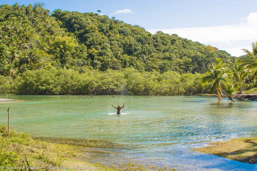 Imagem de um rapaz jogando água para cima e se deliciando na Praia de Jeribucaçu.